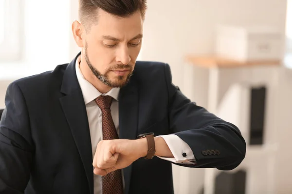 Businessman looking at his wristwatch in office. Time management concept — Stock Photo, Image