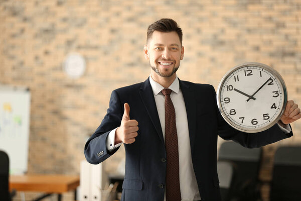 Mature businessman with clock in office. Time management concept