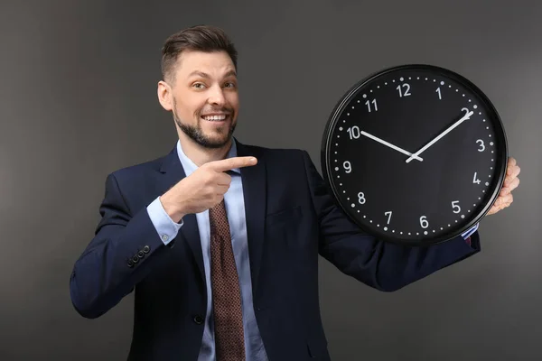 Businessman with clock on dark background. Time management concept — Stock Photo, Image