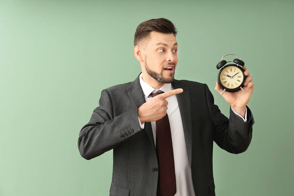 Бизнесмен с будильником на цветном фоне. Концепция управления временем
