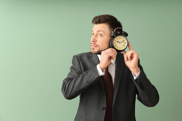 Бизнесмен с будильником на цветном фоне. Концепция управления временем
