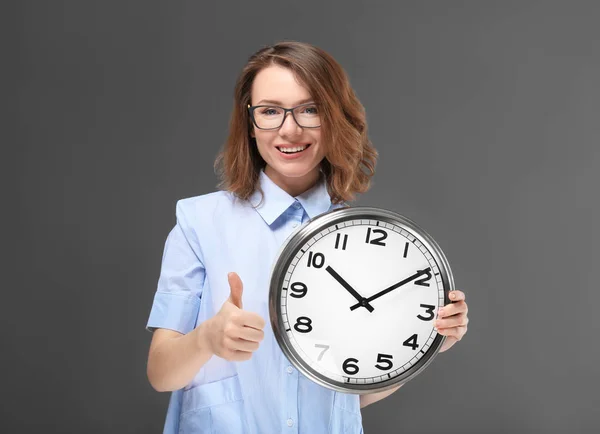 Rijpe vrouw met de klok op een grijze achtergrond. Time management concept — Stockfoto