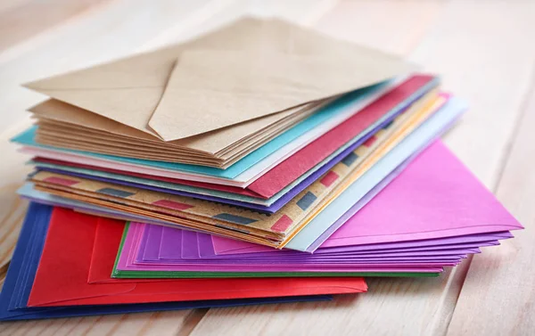 Montón de sobres de colores en la mesa de madera, primer plano. Servicio de correo — Foto de Stock