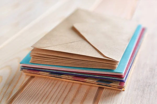 Stack of colorful envelopes on wooden table, closeup. Mail service — Stock Photo, Image