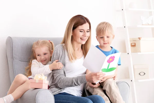 Mother receiving gift box and greeting card from her cute little children at home — Stock Photo, Image