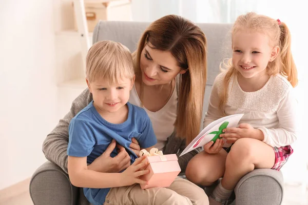 Mother receiving gift box and greeting card from her cute little children at home — Stock Photo, Image