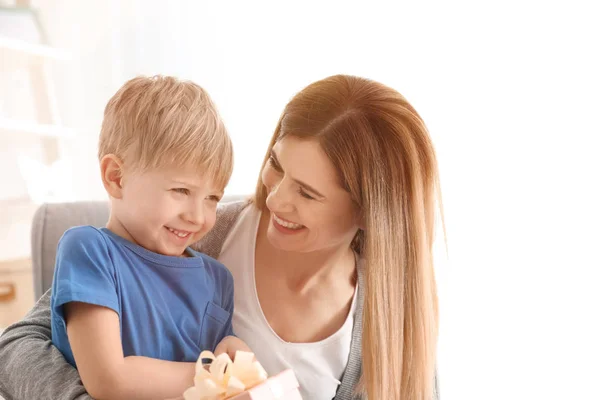 Portret van schattige jongen en zijn lachende moeder met cadeau thuis — Stockfoto