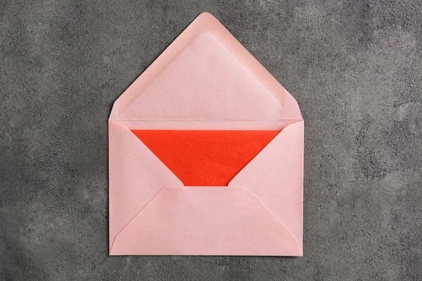 Envelope rosa com cartão no fundo cinza, vista superior. Serviço de correio — Fotografia de Stock