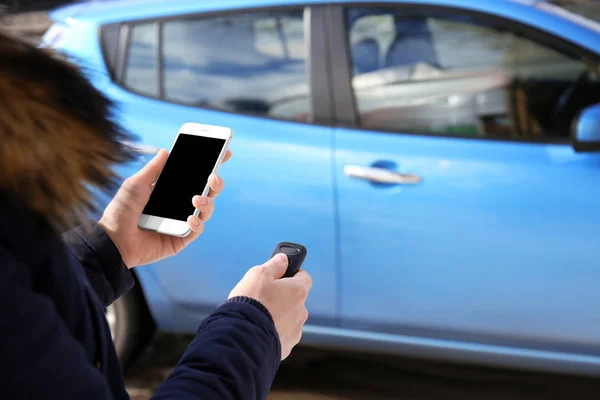 Young woman with phone using car alarm outdoors — Stock Photo, Image