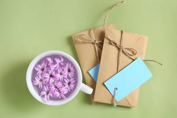 Kopp med blommor och mail kuvert på färgbakgrund — Stockfoto