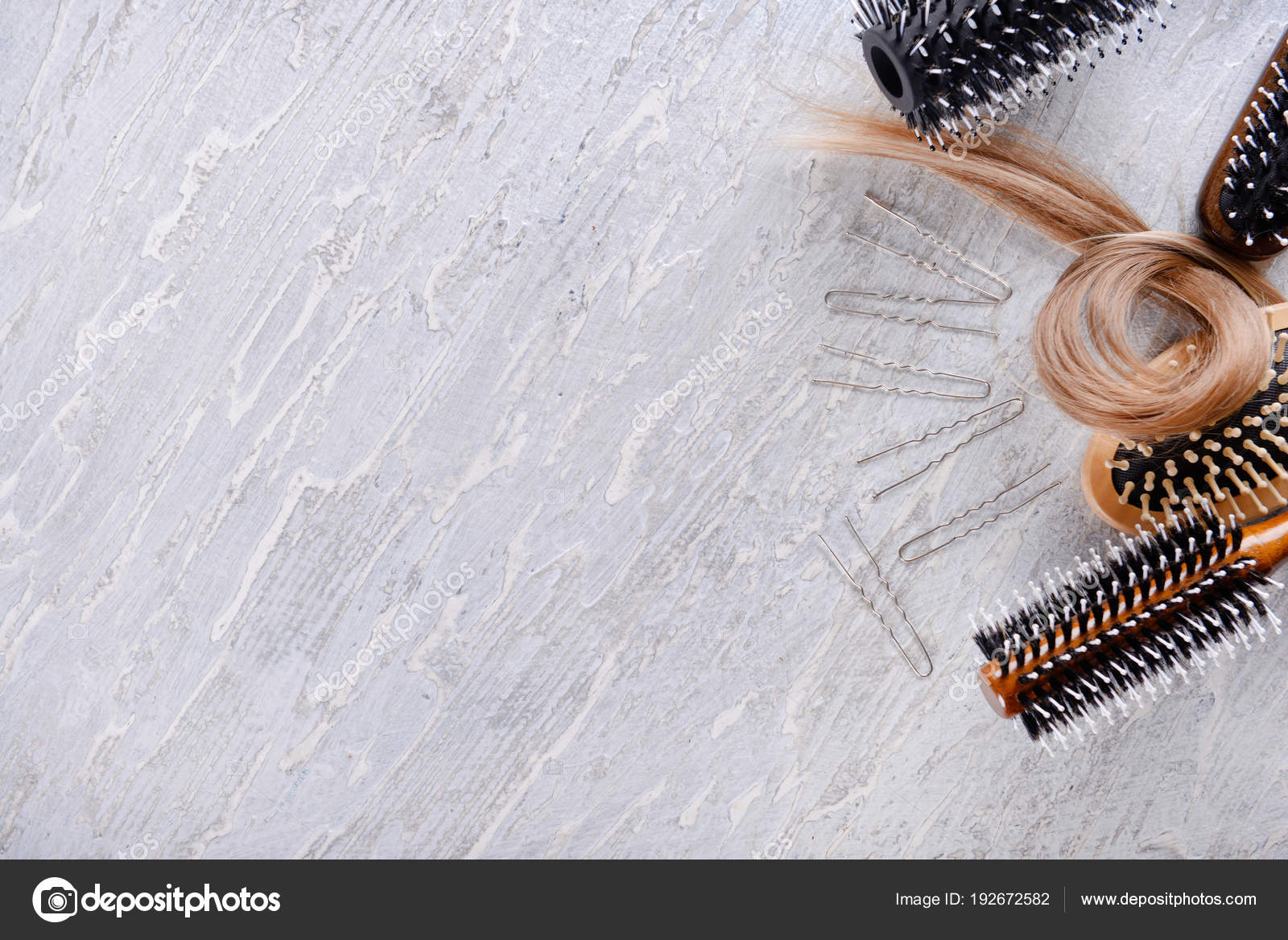 Different brushes and strand of hair on light background Stock Photo by