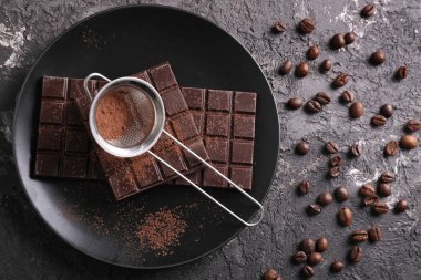 Koyu çikolata ve gri arka plan üzerinde elek ile plaka