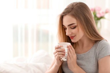 Genç bayan evde kahve içiyor.