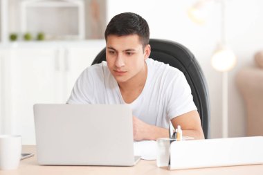 Genç adam masada ev ofis dizüstü bilgisayar ile çalışma