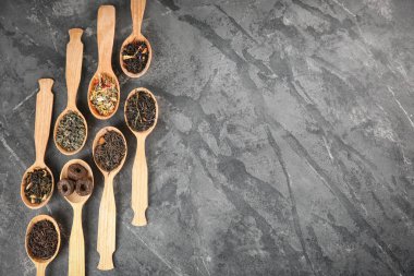 Düz gri dokulu arka plan üzerinde kaşık çay farklı türde, lay