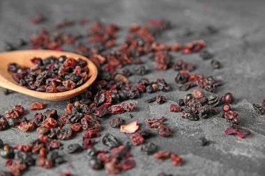 Gri zemin üzerine tahta kaşıkla kuru meyve ve meyve çay