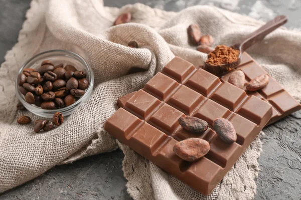 Milk chocolate and bowl of coffee beans on table — Stock Photo, Image