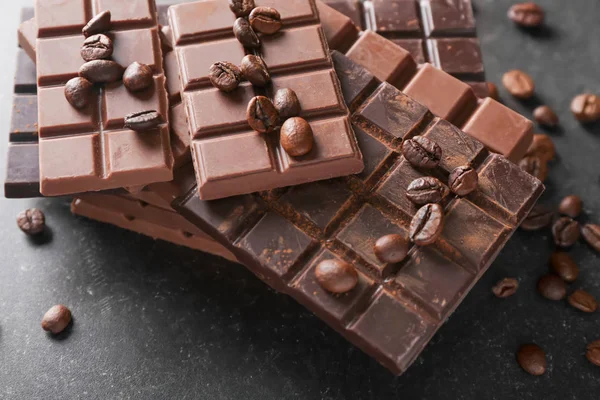 Süße Schokolade mit Kaffeebohnen auf dunklem Hintergrund — Stockfoto