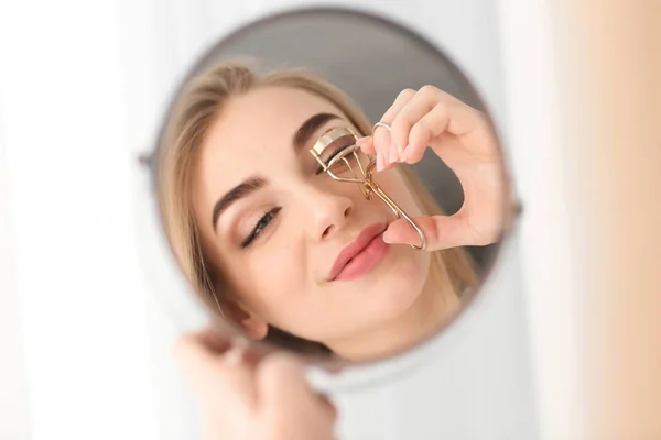 Fiatal nő használ otthon a tükör előtt szempilla hajcsavaró — Stock Fotó