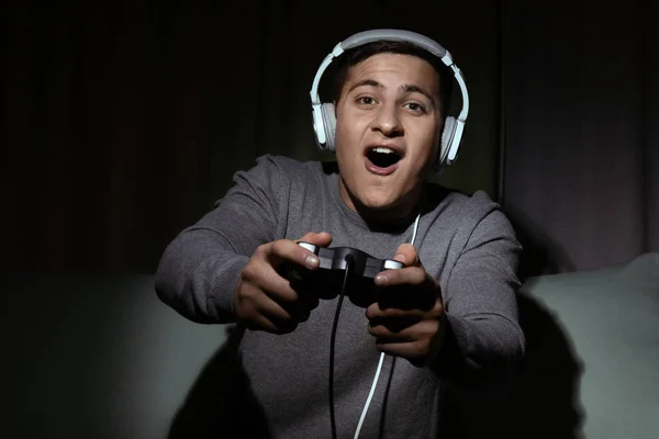 Joven jugando videojuegos en casa en la oscuridad —  Fotos de Stock