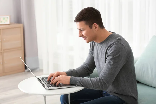 Mladý muž pracující s přenosným počítačem doma — Stock fotografie