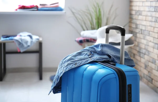 Packed suitcase and denim jacket in room — Stock Photo, Image