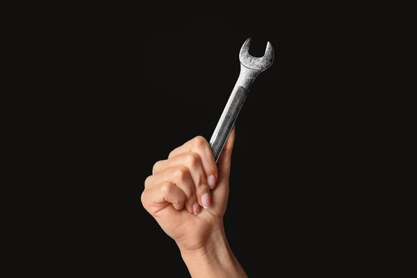 Hand of female car mechanic with wrench on black background — Stock Photo, Image