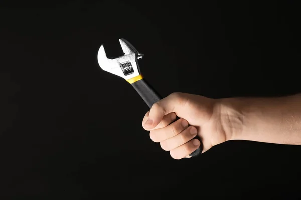 Hand of male car mechanic with adjustable wrench on black background — Stock Photo, Image