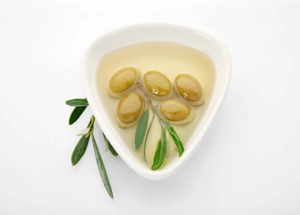 Ciotola con olio e olive in scatola su fondo bianco — Foto Stock