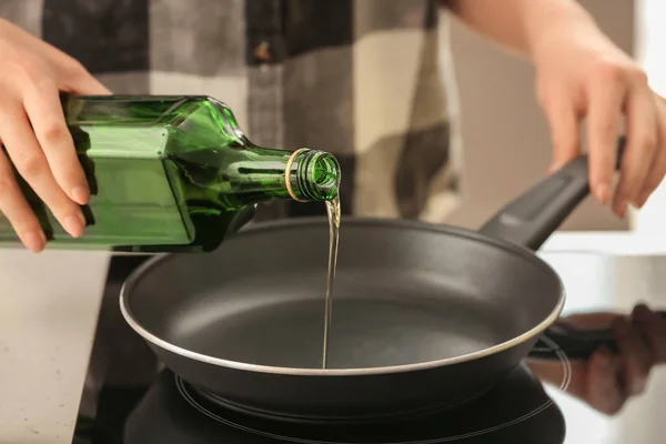 Woman pouring olive oil into frying pan on stove — Stock Photo, Image