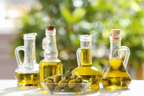 Jarras con aceite de oliva sobre la mesa sobre fondo borroso — Foto de Stock