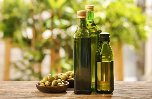 Botellas con aceite de oliva sobre la mesa sobre fondo borroso — Foto de Stock