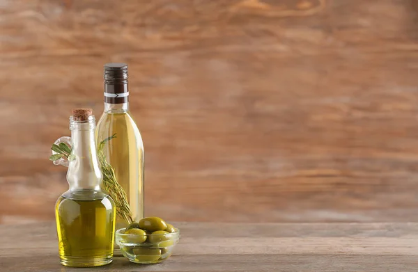Botol dengan minyak zaitun dengan latar belakang kayu — Stok Foto