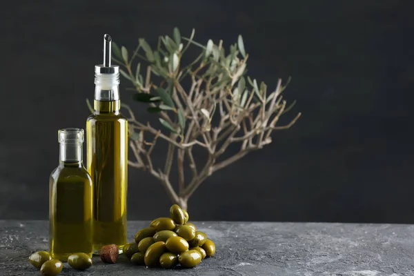 Botellas con aceite de oliva sobre la mesa sobre fondo oscuro — Foto de Stock