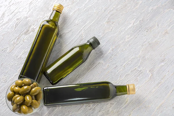 Lahve s olivovým olejem na světlé pozadí — Stock fotografie