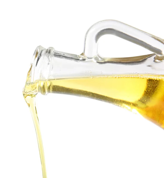 Gießen von Olivenöl aus Glaskanne auf weißem Hintergrund — Stockfoto
