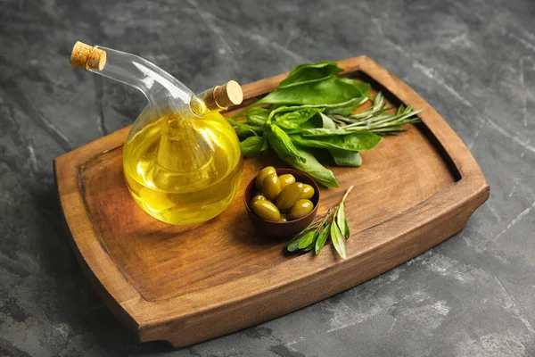 Бутылка с маслом и оливками на деревянной доске — стоковое фото