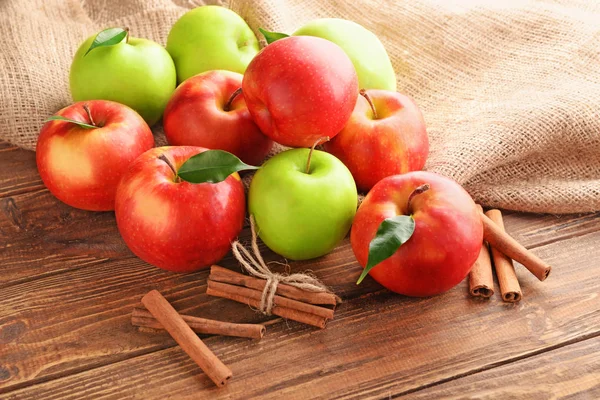 Manzanas frescas y palitos de canela sobre fondo de madera — Foto de Stock