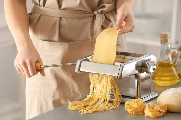 Vrouw maakt noedels met pasta machine aan tafel — Stockfoto