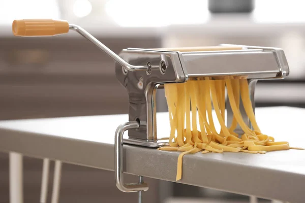Metalen Pastamachine met deeg op tafel tegen onscherpe achtergrond — Stockfoto