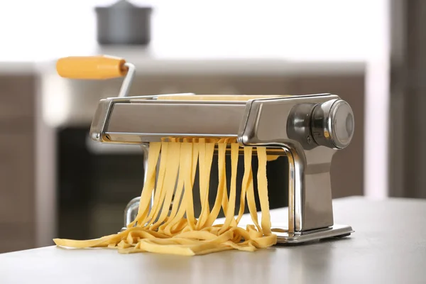 Metalen Pastamachine met deeg op tafel tegen onscherpe achtergrond — Stockfoto