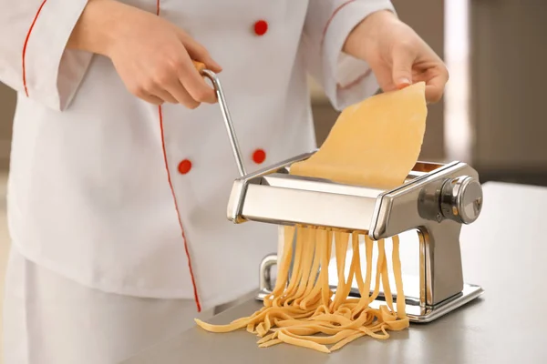 Vrouwelijke chef-kok noedels met Pastamachine aan tafel maken — Stockfoto