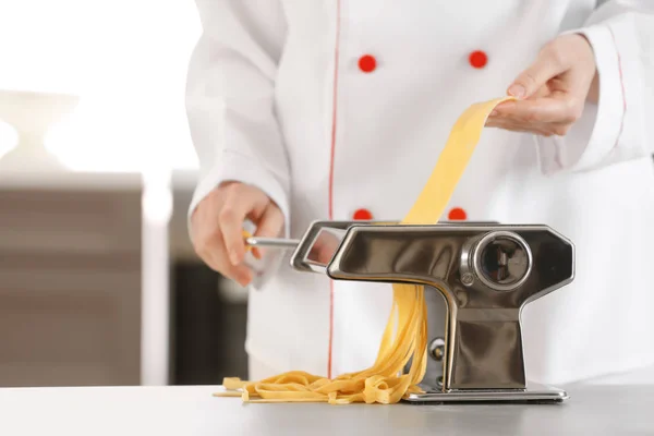 Vrouwelijke chef-kok noedels met Pastamachine aan tafel maken — Stockfoto