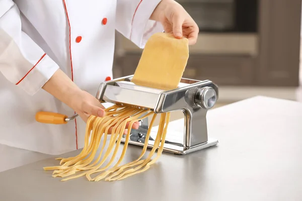 Female chef making noodles with pasta machine at table — Stock Photo, Image