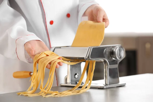 Vrouwelijke chef-kok noedels met Pastamachine aan tafel maken — Stockfoto