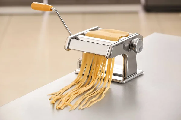 Metal pasta maker with dough on table — Stock Photo, Image