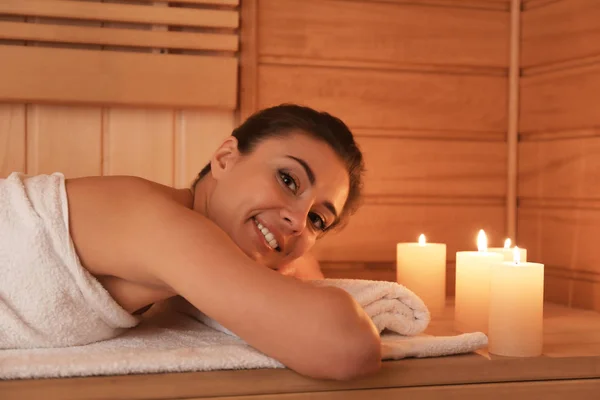 Mujer joven acostada en un banco de madera en la sauna — Foto de Stock