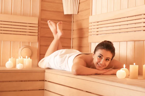 Mujer joven acostada en un banco de madera en la sauna — Foto de Stock