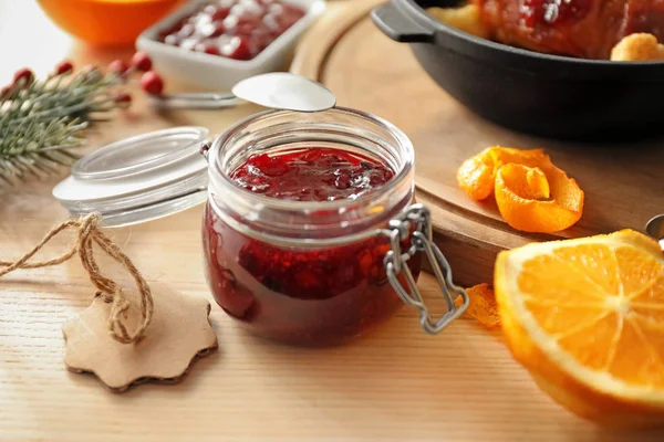 Jar with delicious cranberry sauce and products on table — Stock Photo, Image