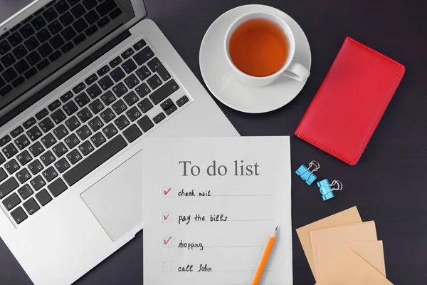 Samenstelling met to-do lijst en laptop op donkere tafel — Stockfoto